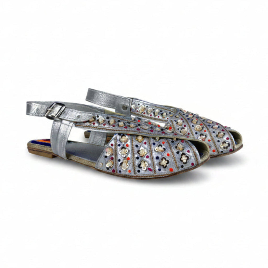 Silver flat shoes with colorful embellishments on a white background