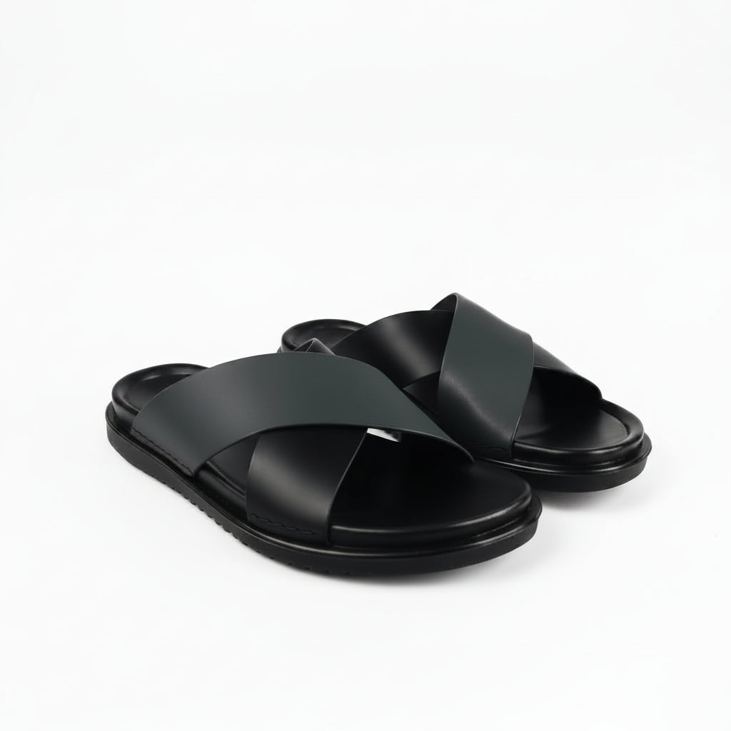 A pair of black leather slide sandals with crisscrossing straps and thick black soles, photographed on a clean white background.