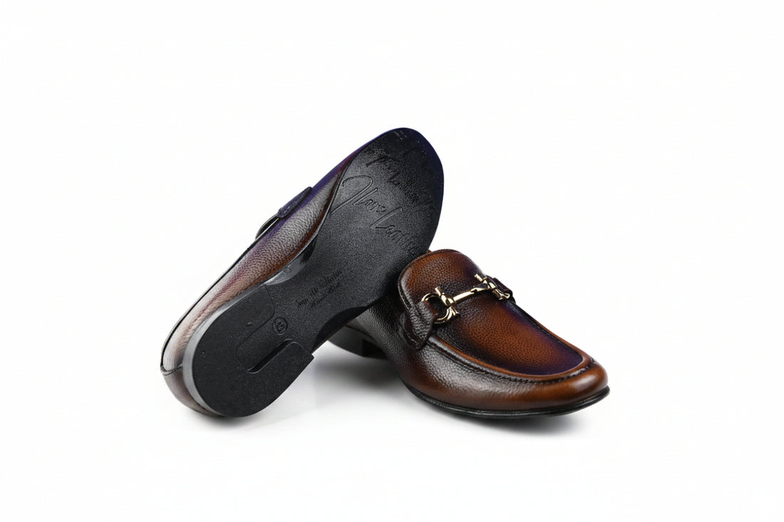 A pair of black pebbled loafers with a silver-tone horsebit detail across the vamp, displayed on a clean white background.