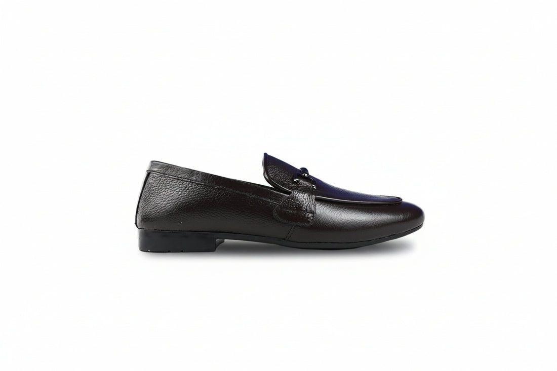 A pair of black  penny loafers with a decorative strap and small metal buckle detail across the vamp, shown on a plain white background.