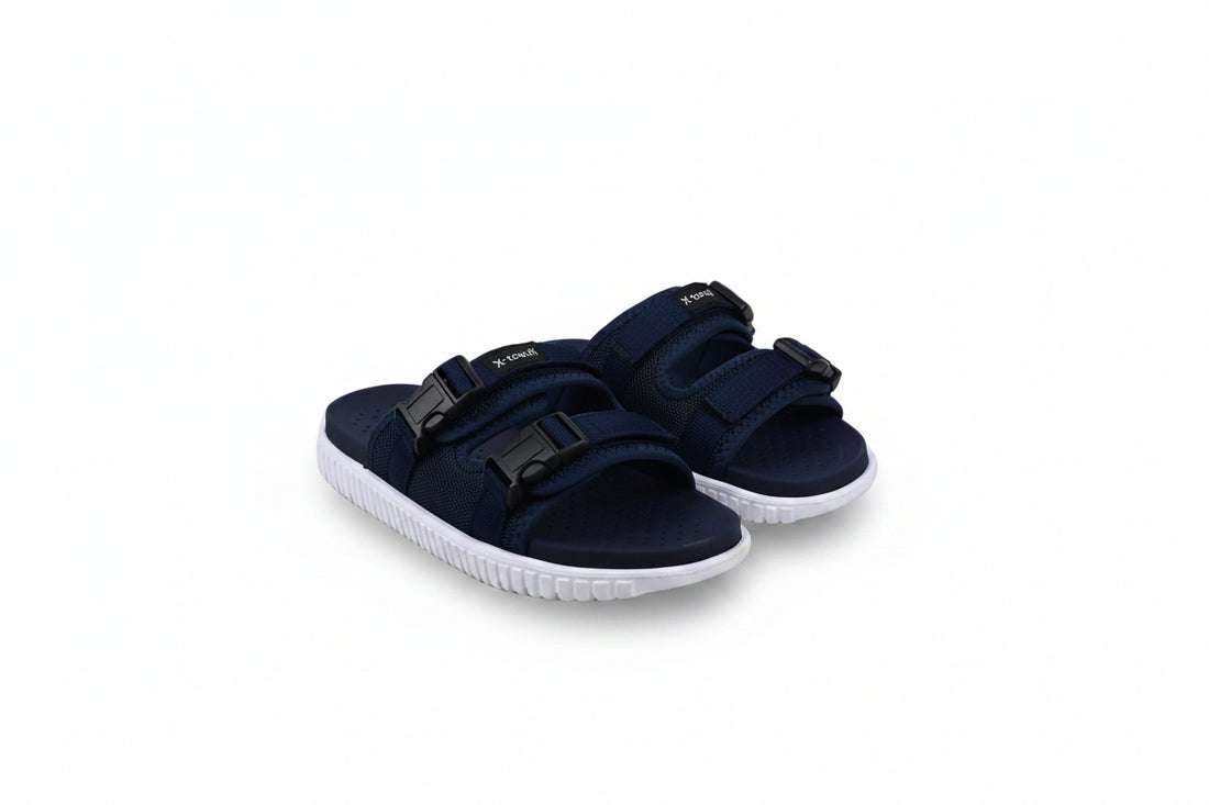 A pair of navy blue double-strap slide sandals with white soles, photographed on a white studio background.