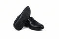 A pair of black slip-on loafers, with one shoe turned to show the textured outsole, set against a plain white background.