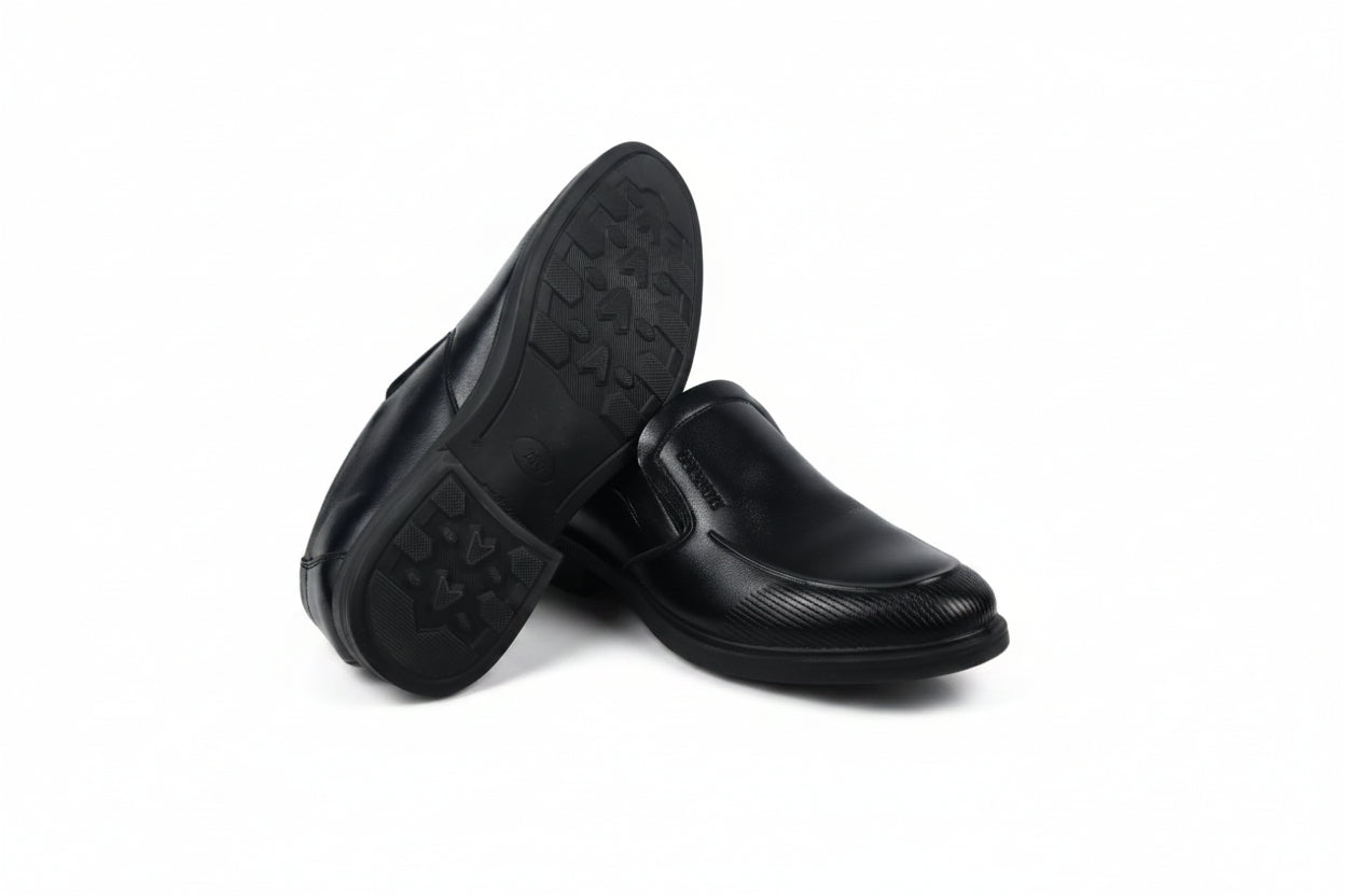 A pair of black slip-on loafers, with one shoe turned to show the textured outsole, set against a plain white background.