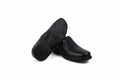 A pair of black slip-on shoes shown on a white background, with one shoe standing upright to display the sole and the other lying on its side to show the side profile.