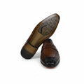A pair of men's brown penny loafers, with one shoe standing upright to show the textured outsole and the other lying flat to show the side profile, set against a plain white background.