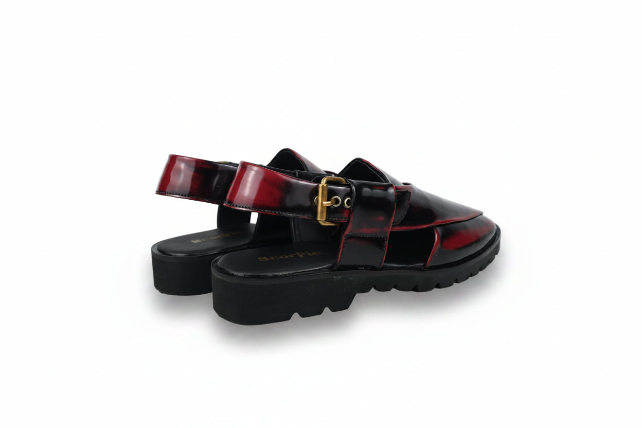 A pair of black platform mule sandals with glossy red side panels and a gold buckle detail, photographed on a white studio background.