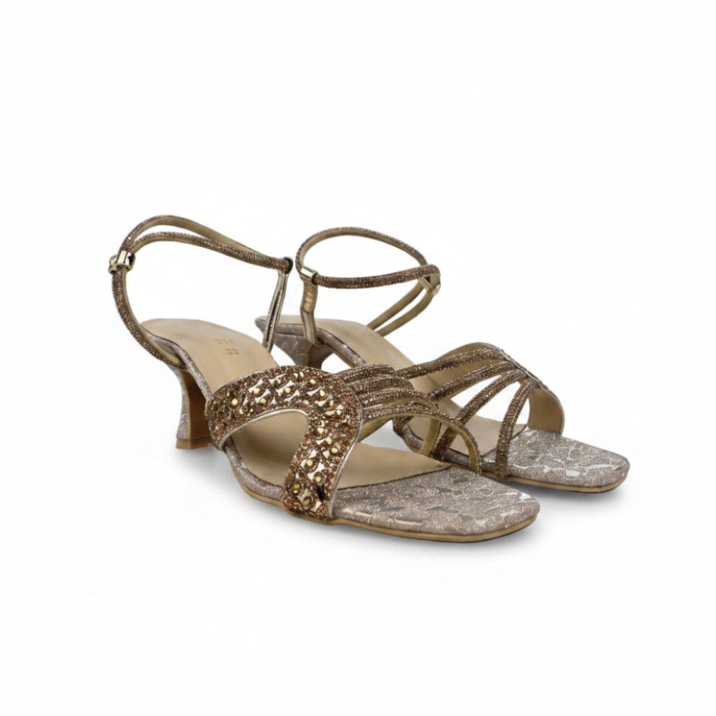 A pair of women's heeled sandals in metallic gold and silver, featuring textured straps and a low block heel, photographed on a light gray background.