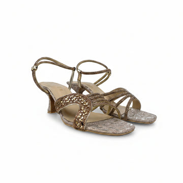 A pair of women's heeled sandals in metallic gold and silver, featuring textured straps and a low block heel, photographed on a light gray background.