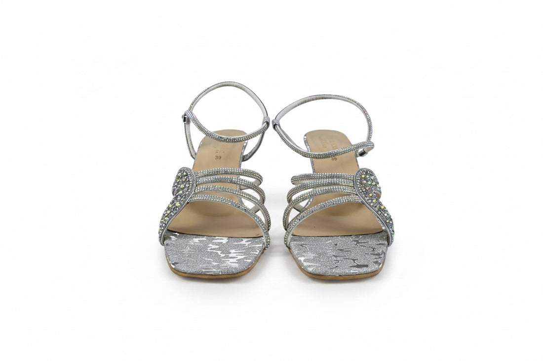 A pair of women's heeled sandals in metallic gold and silver, featuring textured straps and a low block heel, photographed on a light gray background.