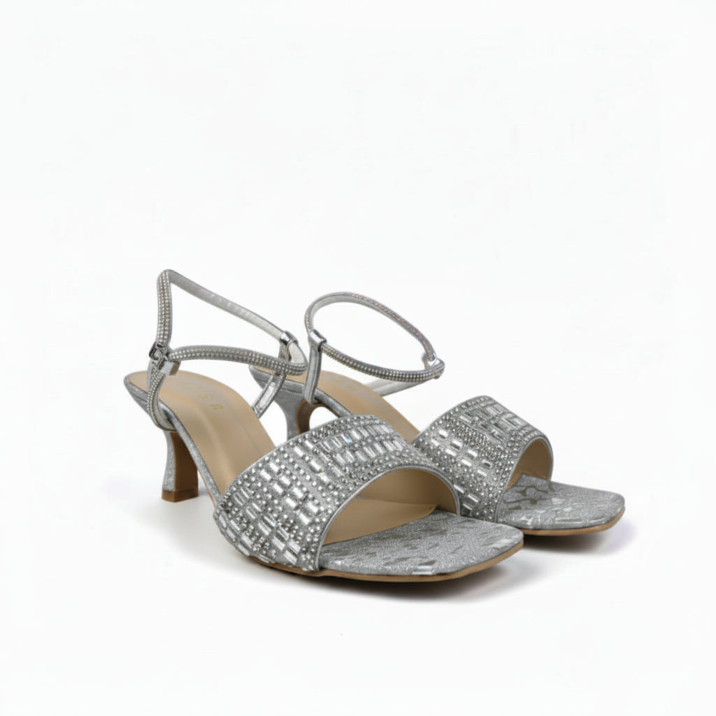 A pair of women's silver heeled sandals with rhinestone-embellished straps and a textured metallic upper, shown on a light gray studio background.