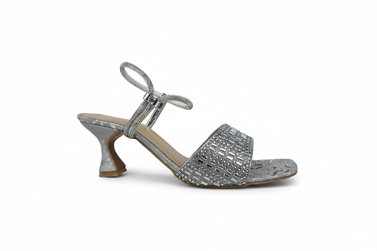 A single women's heeled sandal in metallic silver with rhinestone embellishments, a square toe, and a low kitten heel, shown against a light gray background.