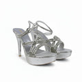 A pair of metallic silver high-heeled sandals with platform soles and crisscross ankle straps, photographed against a white studio backdrop.