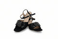 A pair of black open-toe slingback sandals with ankle straps and large black beaded floral embellishments on the toes, photographed against a white studio background.