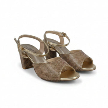 A pair of women's heeled sandals with a textured metallic gold glitter finish, featuring an open toe, ankle strap, and block heel, set against a plain light gray studio background.