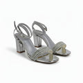 A pair of women's silver metallic block-heel sandals with rhinestone-embellished straps, shown on a white studio background.