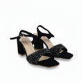 A pair of black high-heeled sandals with ankle straps and sparkling silver embellishments on the square toes, shown on a white studio background.