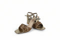 A pair of women's metallic gold block-heel sandals with embellished straps and a block heel, shown on a light gray studio background.