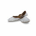 A pair of traditional Indian mule slippers (chappals) made of white printed cotton canvas with brown leather trim and lining, displayed on a light gray fabric background.