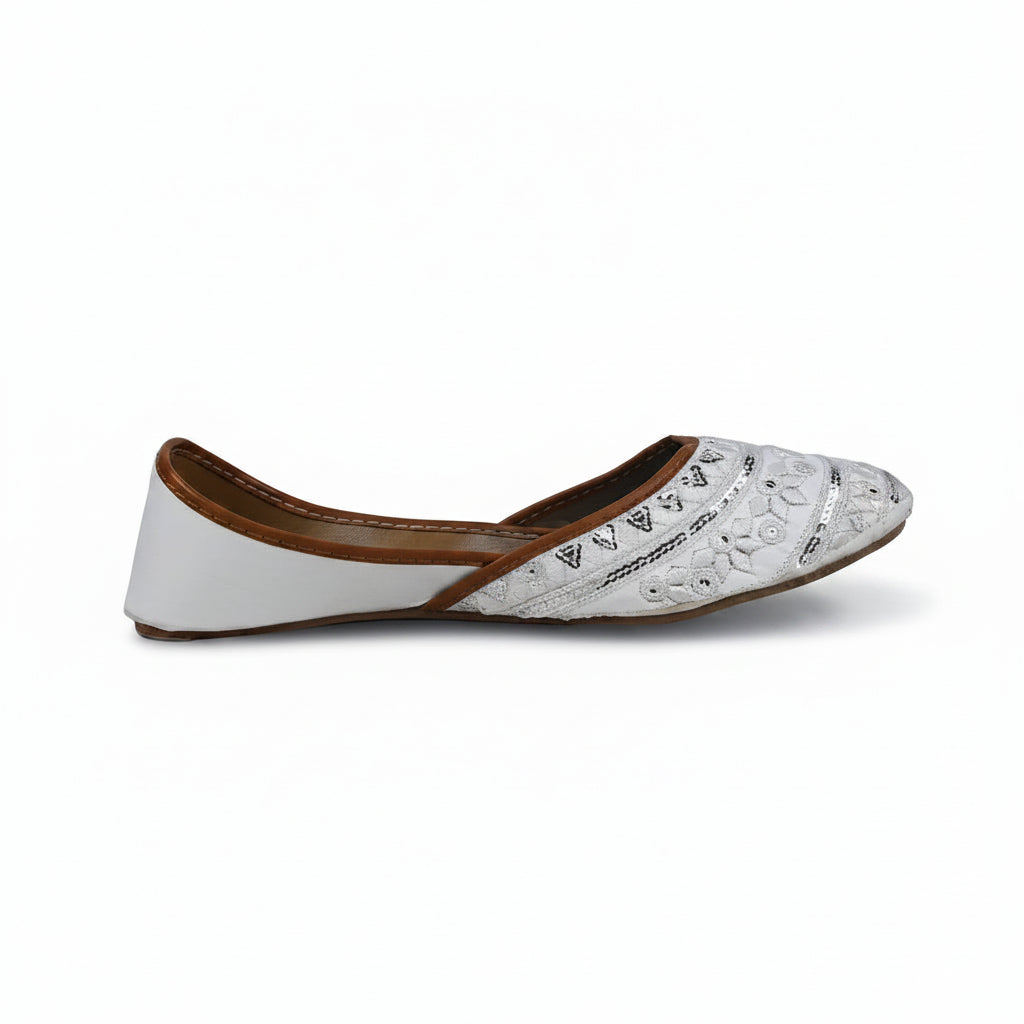 A single white flat shoe with silver metallic embroidery on the toe and a brown inner lining, shown from the side against a light gray background.