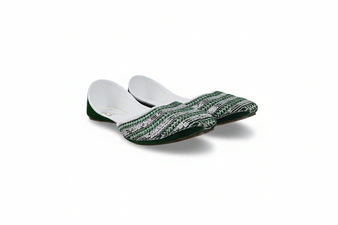 A pair of traditional Indian flat shoes (mulej) featuring a green and white patterned woven upper, green soles, and white inner lining, displayed on a light gray fabric background.
