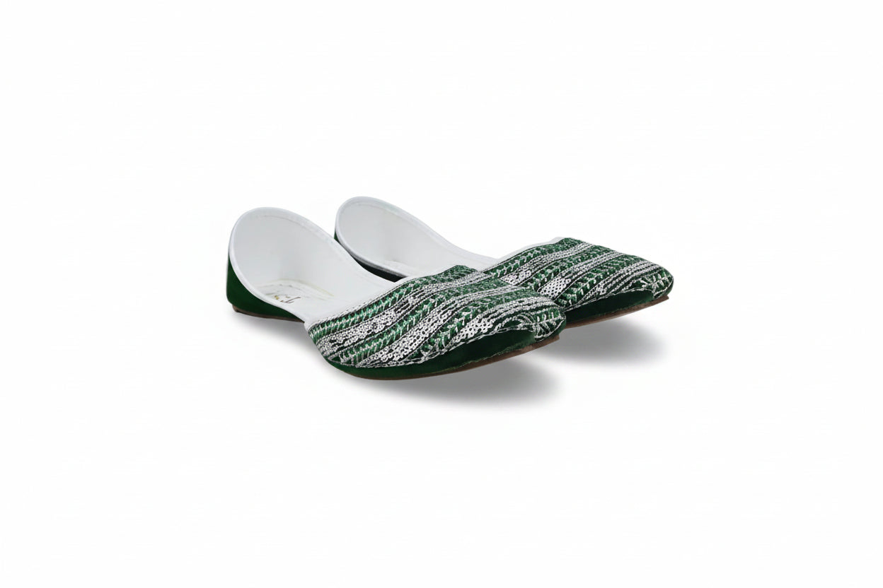 A pair of traditional Indian flat shoes (mulej) featuring a green and white patterned woven upper, green soles, and white inner lining, displayed on a light gray fabric background.
