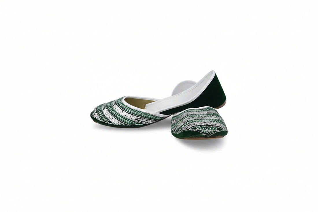A pair of traditional Indian flat shoes (mulej) featuring a green and white patterned woven upper, green soles, and white inner lining, displayed on a light gray fabric background.
