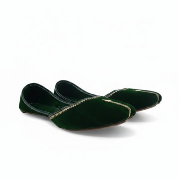 A pair of dark green velvet flat shoes with gold embroidered detailing along the toe, displayed on a light gray fabric background.