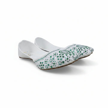 A pair of white flat slip-on shoes decorated with green sequins and beadwork, displayed on a light gray surface.