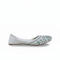 A single white flat shoe with green and blue floral embellishments on the toe, shown against a light gray background.