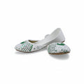 A pair of white flat shoes with green and silver embroidered patterns on the toe caps, displayed against a light gray fabric backdrop.