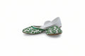 A pair of white flat shoes with green floral embroidery on the pointed toes, photographed against a light gray fabric backdrop.
