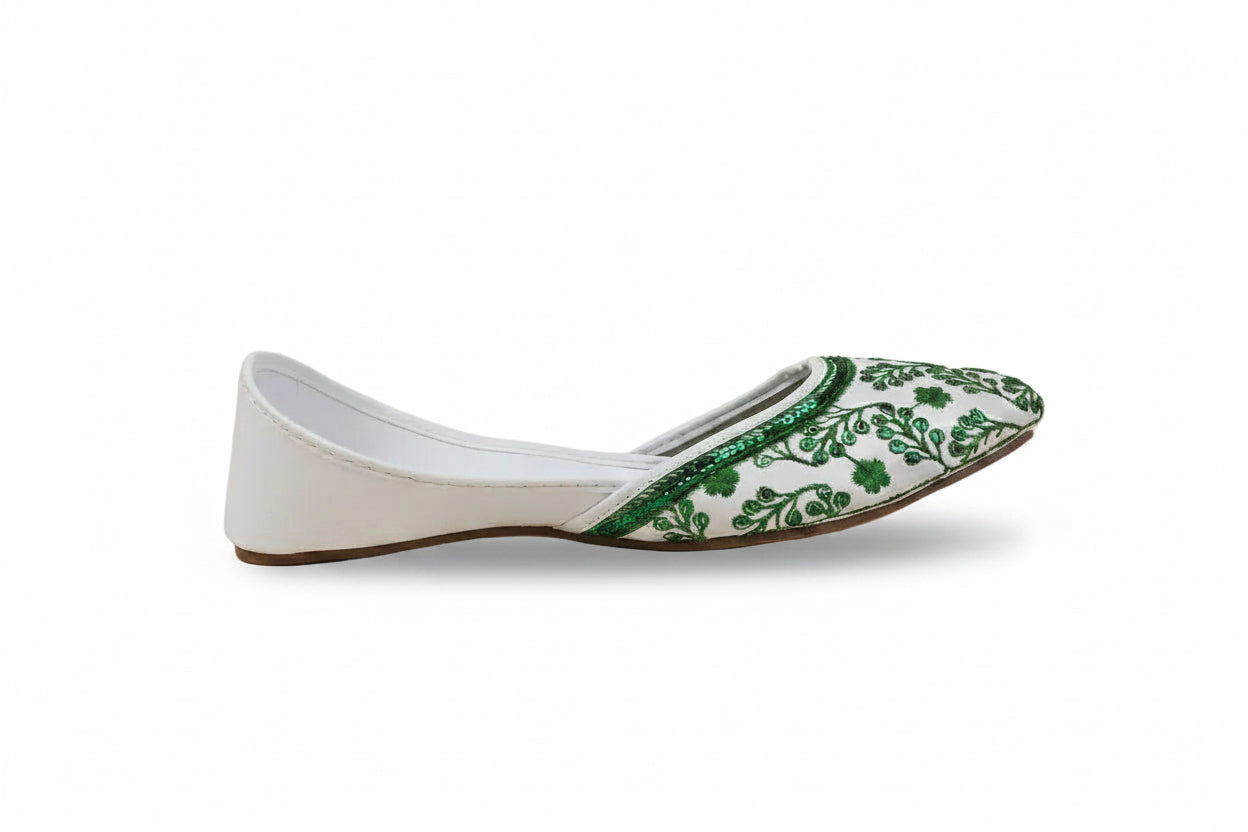 A single white flat shoe with green floral embroidery and beadwork on the toe cap, shown in profile against a light gray background.