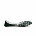 A single dark green velvet flat shoe with intricate silver and green embroidered patterns on the toe, shown against a light gray background.