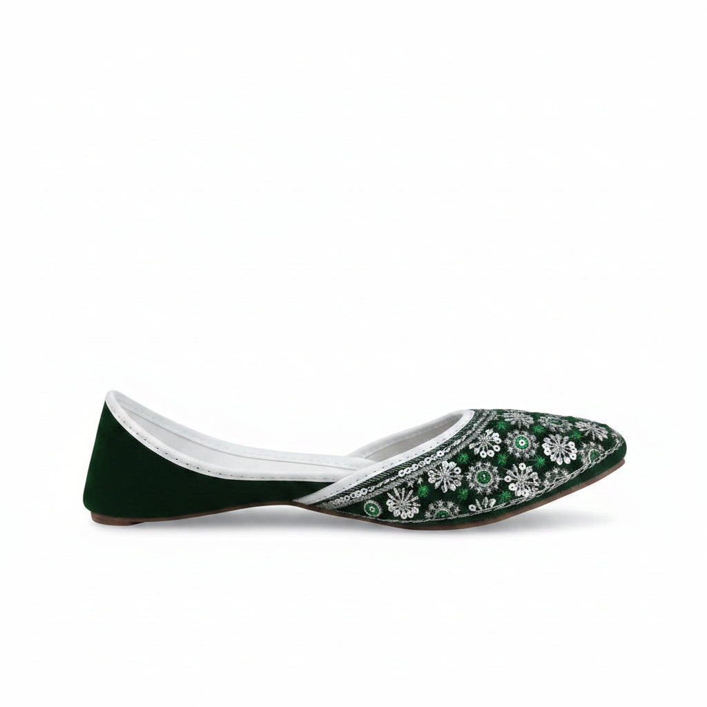 A single dark green velvet flat shoe with intricate silver and green embroidered patterns on the toe, shown against a light gray background.