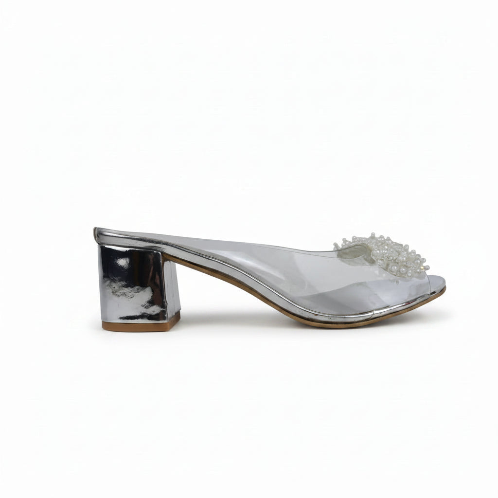 A single silver metallic mule sandal with a chunky block heel and a clear embellished toe strap, shown from a side profile on a light gray surface.