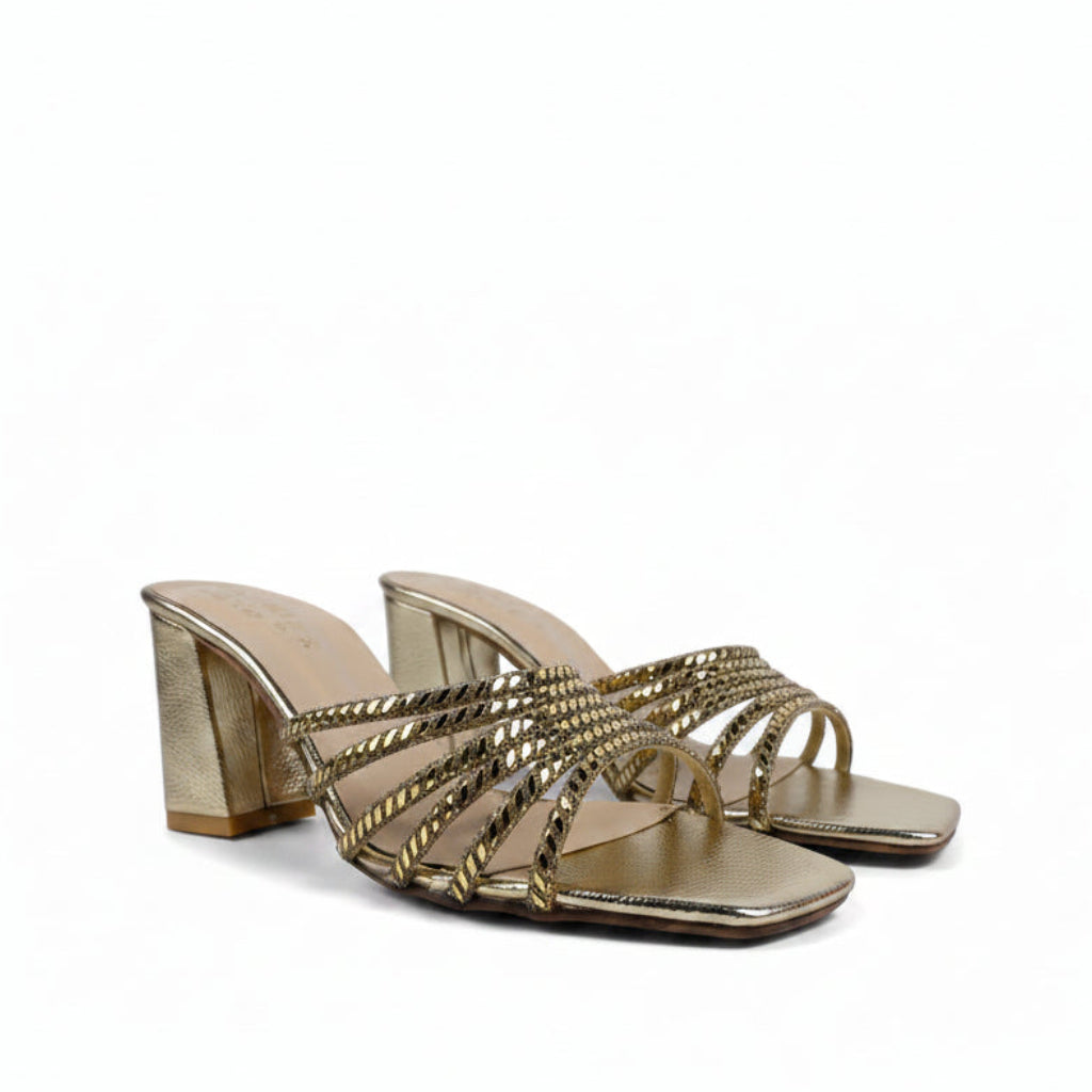 A pair of metallic gold block-heel slide sandals with multiple twisted rope-style straps, shown on a light gray fabric background.