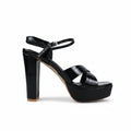 A single black patent leather high-heeled sandal with a block heel, open toe, and ankle strap, shown from a side profile against a white studio background.