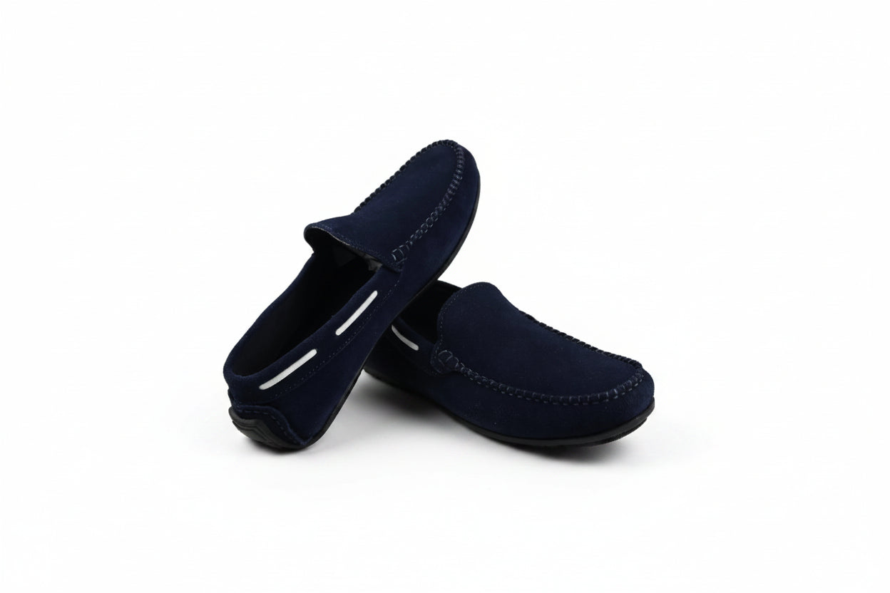 A pair of dark navy blue suede moccasin-style slip-on shoes photographed on a white studio background.