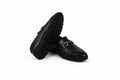 A pair of black leather loafers with a textured woven pattern on the sides and a gold-tone horsebit detail on the toe, displayed on a white studio background.