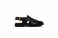 A single black leather sandal with a chunky platform sole, cutout straps, and a black ankle strap with a gold buckle, shown in profile against a light gray background.