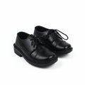 A pair of black leather lace-up shoes with low block heels, photographed on a light gray studio background.