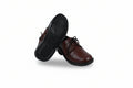 A pair of dark brown leather lace-up shoes with black soles, one standing upright and the other tilted on its side to show the tread, set against a plain white background.