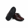 A pair of men's brown leather lace-up dress shoes, with one shoe turned upside down to show the black textured outsole, set against a plain white studio background.