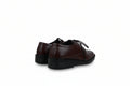A pair of dark brown leather lace-up shoes with black soles, shown from a side-rear angle against a light gray fabric backdrop.