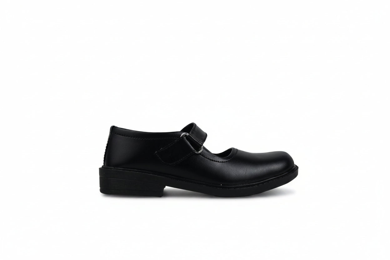 A single black leather Mary Jane school shoe with a hook-and-loop strap closure, shown from a side profile against a light gray fabric backdrop.