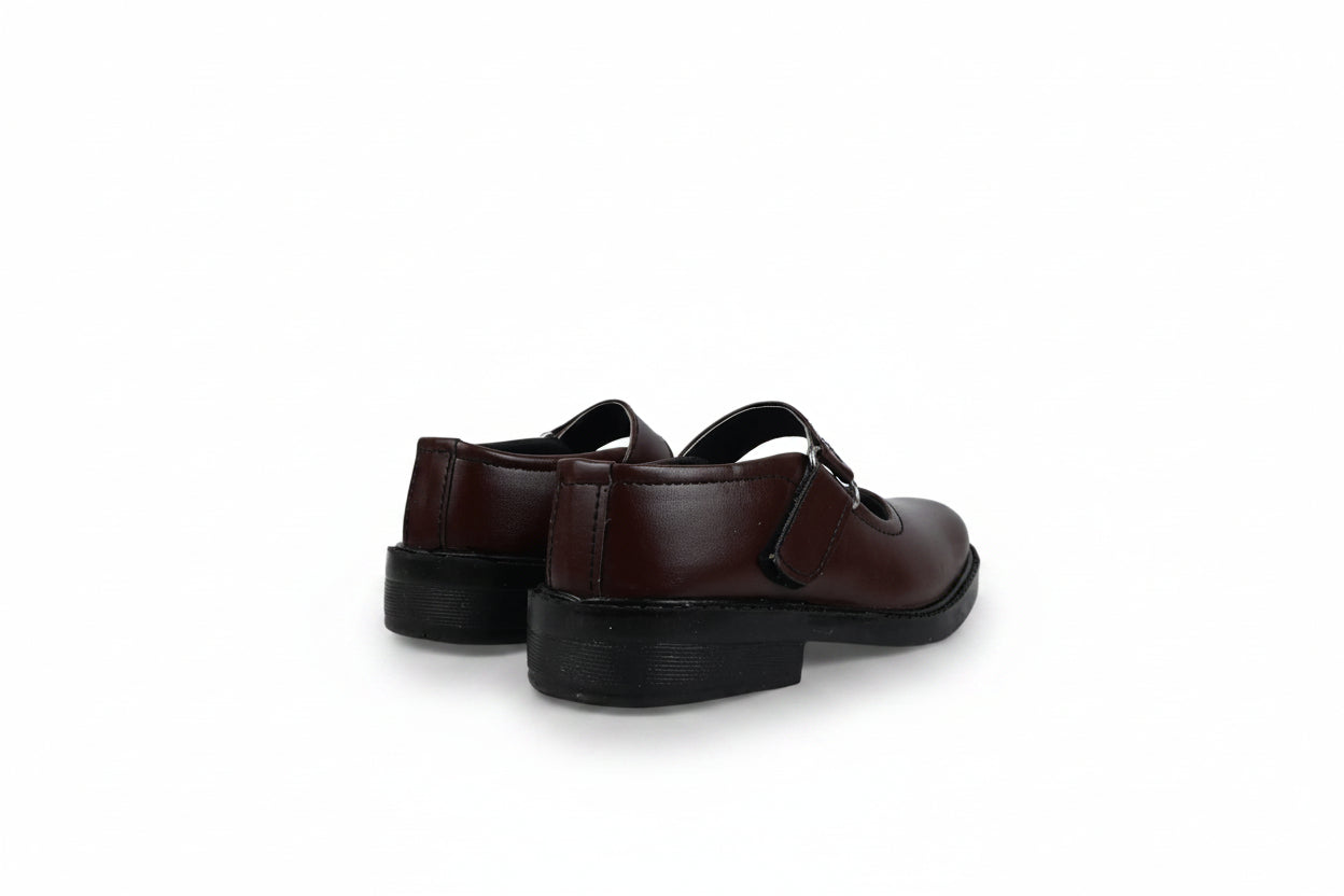A pair of dark brown leather Mary Jane shoes with black soles, shown from a rear three-quarter angle against a white studio backdrop.