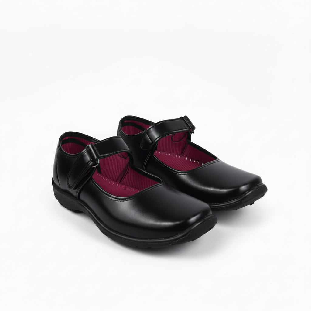 A pair of black Mary Jane school shoes with magenta pink lining, shown on a white studio background.