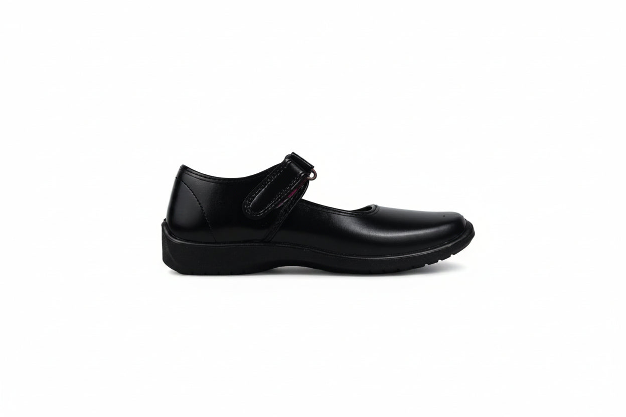 A single black leather Mary Jane shoe with a hook-and-loop strap closure, shown in profile against a light gray fabric backdrop.