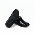 A pair of black leather slip-on shoes, with one shoe standing upright to show the textured black sole and the other lying on its side to display the glossy black toe cap, set against a plain white studio background.