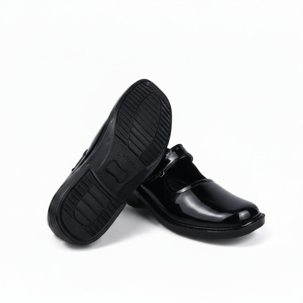 A pair of black leather slip-on shoes, with one shoe standing upright to show the textured black sole and the other lying on its side to display the glossy black toe cap, set against a plain white studio background.